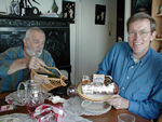 Mark shows off birthday cake while Marc sneaks more wine into Mark's glass