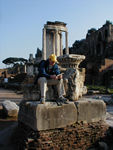 Reading with Temple of Vesta in the background.  Vesta was the goddess who protected the domestic hearth.  The round shape comes from the round huts of very ancient Romans.  A sacred fire had to be kept buring constantly.  Unsurprisingly, the temple was destroyed by fires several times.