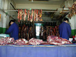 Meat laid out in butcher's shop.  Seeing the butcher's cutting off chunks with an axe was unnerving.  So, was the morning delivery.  A pickup with the bed filled with carcasses pulls up, the bed is uncovered, and the butcher and driver haul a couple into the shop