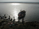 A boat with the body of a sadhu stops near the laundry for pictures.  Then they sailed a bit farther out and dumped the body, the stretcher, and the cloths overboard.